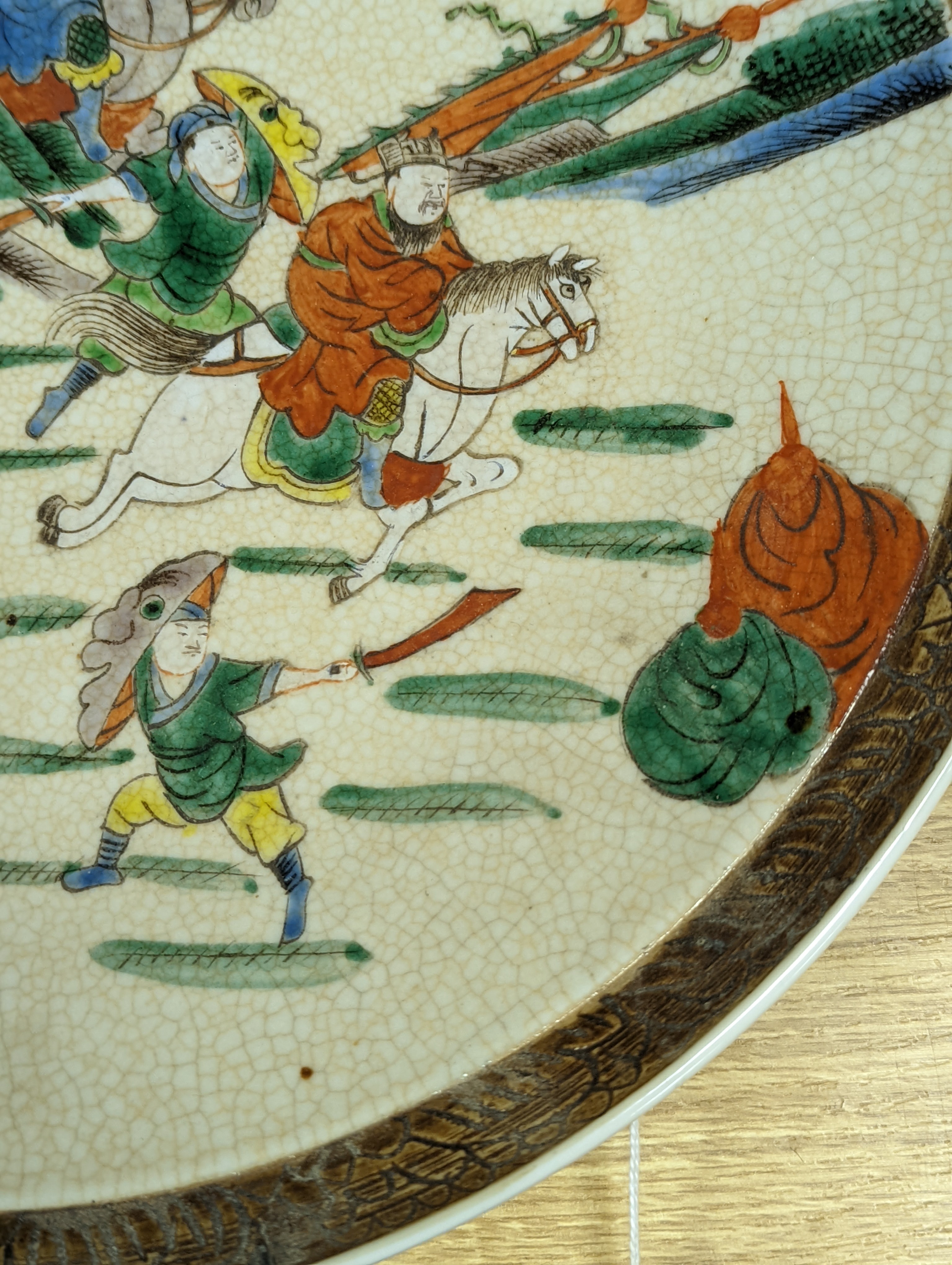 A Chinese crackle glaze dish, early 20th century, depicting a battle scene 33cm